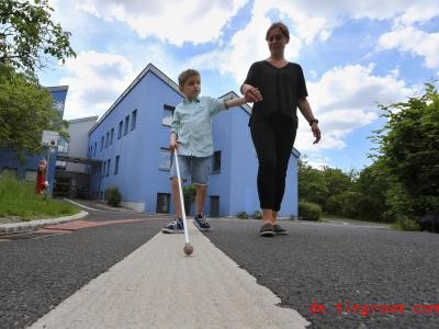  Der taubblinde Lucas läuft mit seinem Blindenstock und seiner Erzieherin Stefanie Tröster vor dem Blindeninstitut. Foto: Karl-Josef Hildenbrand/dpa 